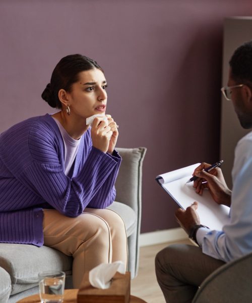 Anxious emotional young woman talking to her psychologist